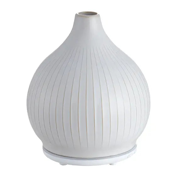 Dyfuzor zapachowy Pistil White 250 ml łączy funkcjonalność dyfuzora ultradźwiękowego z formą dekoracyjnej ceramiki. Jego pełna, harmonijna sylwetka inspirowana kształtem pąka oraz regularne pionowe żłobienia nadają mu rzeźbiarski charakter. Ciepła biel i subtelny pierścień światła przy podstawie wprowadzają do wnętrza spokój, miękkość i elegancję.
