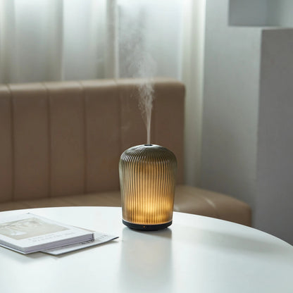 Dyfuzor zapachowy na olejki eteryczne&nbsp;Cactus 130 ml wyróżnia się organiczną formą inspirowaną kaktusem. Pionowo ryflowane szkło i zaokrąglona górna część nadają mu dekoracyjny charakter. Ciepłe białe światło przenika przez szklaną obudowę, podkreślając jej strukturę i tworząc przytulną poświatę.